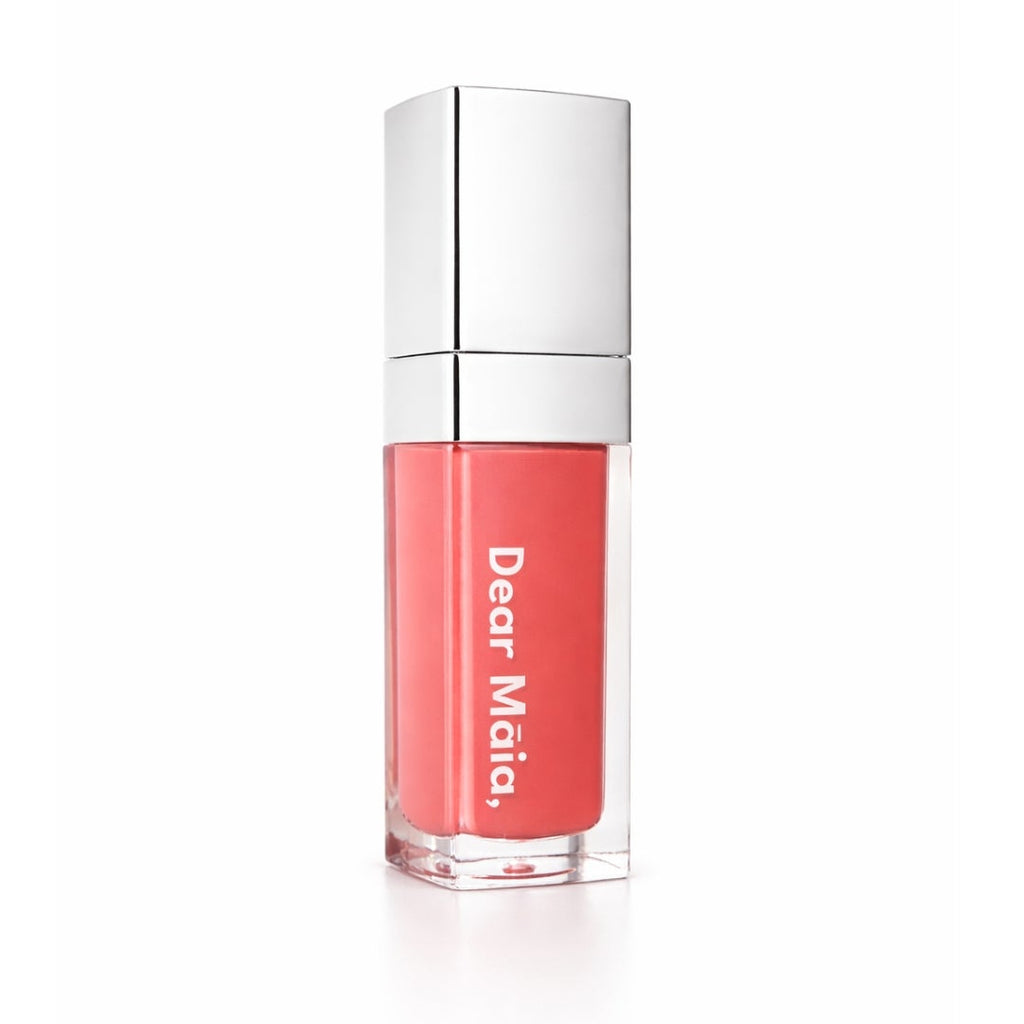 Luminous liquid blush acrylic bottle with silver cap and a peachy coral blush shade inside on a white background with the Dear Māia logo