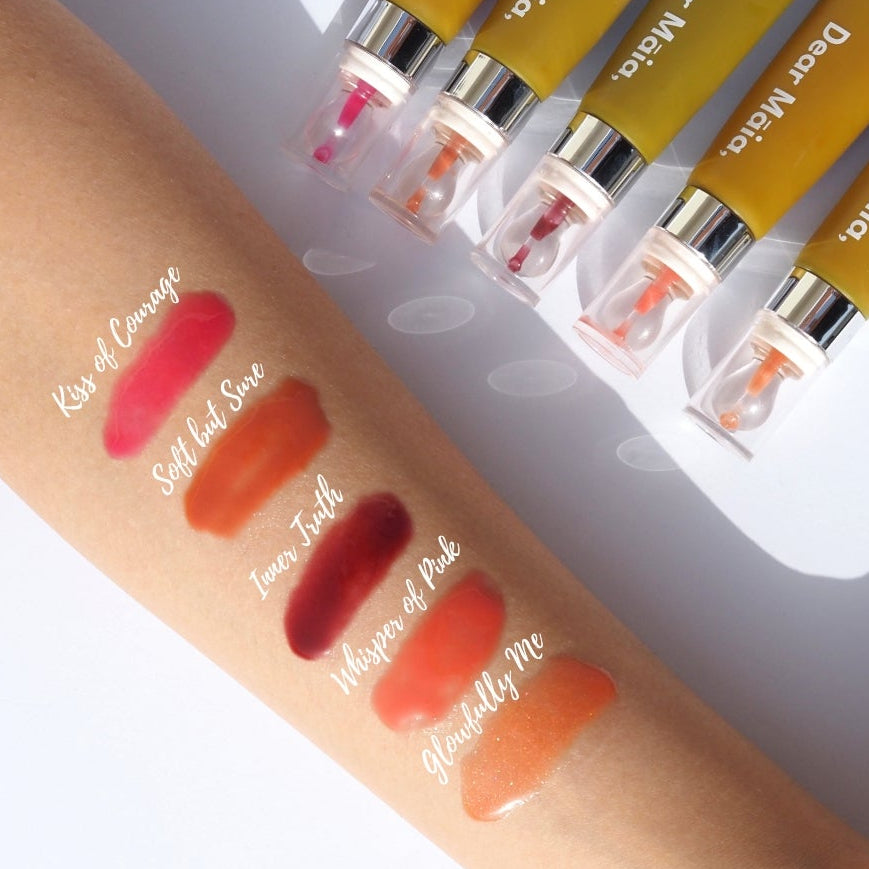Dear Māia Lip Treatment displayed on a hand with swatches, set against a white background.