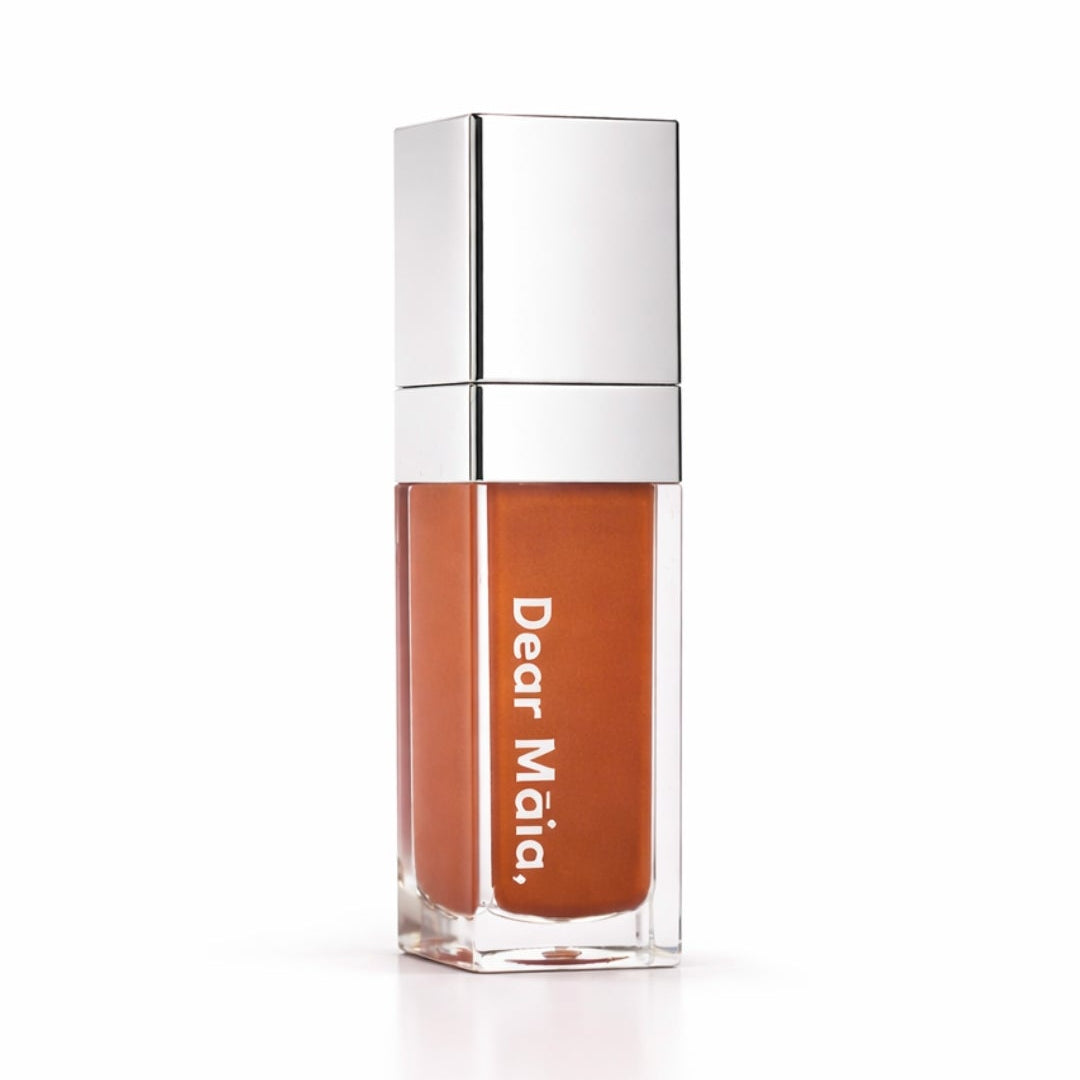 Luminous liquid blush acrylic bottle with silver cap and a peachy golden brown blush shade inside on a white background with the Dear Māia logo
